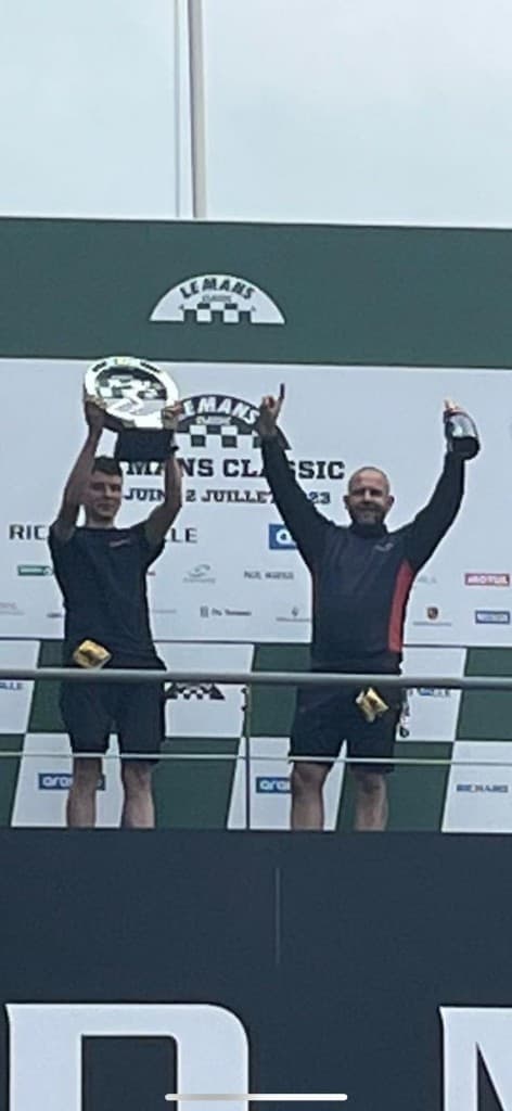 Podium celebration at Le Mans Classic with trophy raised