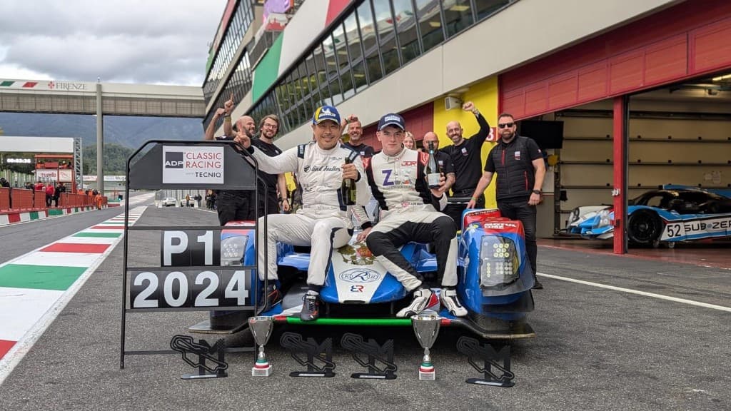 Race winners perched on LMP prototype nose with P1 2024 pit board at Mugello